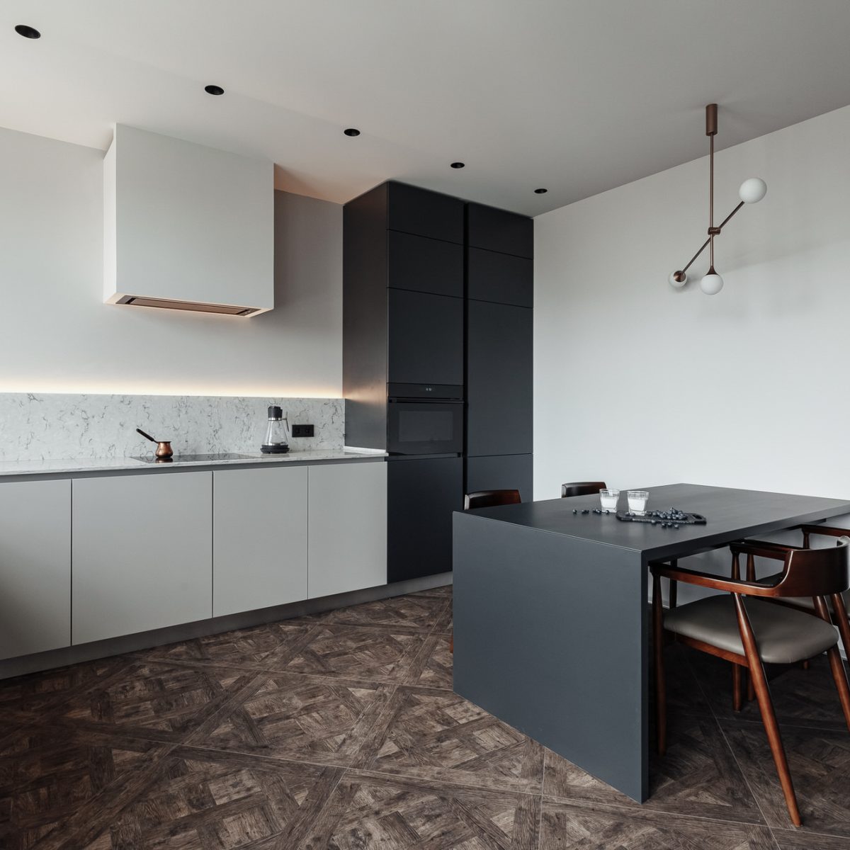 bright kitchen with dark table, convenient location of kitchen accessories and equipment, modern style, White walls, marble working surface and parquet floor.